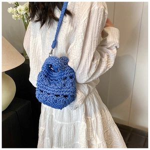 Detailed view of royal blue chunky knit shoulder bag with woven strap and metal hooks
