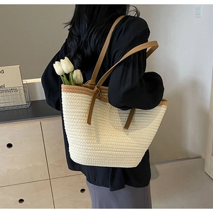 Detail view of woven straw tote bag texture with brown leather strap and flowers
