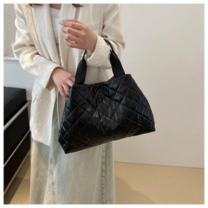 Détail du sac cabas matelassé noir avec finition brillante et larges anses en textile