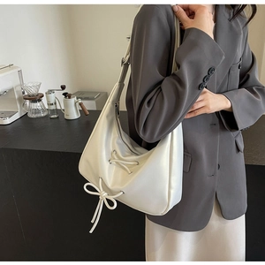 Close-up of white PU leather hobo bag featuring a decorative bow knot and silver zipper