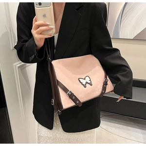 Detail of pink PU leather crossbody bag with brown trim and butterfly applique