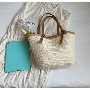 Close-up of woven straw tote bag with brown handles and summer aesthetic props