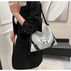 Silver hobo bag with white butterfly patch and black buckle shown in use