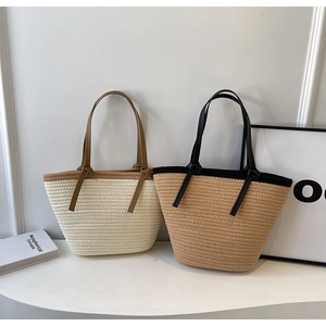 Detail of woven straw tote bags in beige and light brown with leather straps