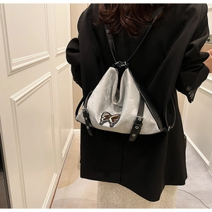 Silver-grey faux leather backpack on model featuring a chic butterfly design and black straps