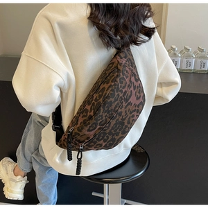 Close-up of leopard print canvas crossbody bag worn by a model in a street style look