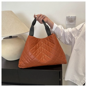 Détail du cabas matelassé orange avec poignées en toile noire dans un cadre de vie
