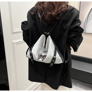 Detail of silver origami backpack showing butterfly embroidery and buckle strap