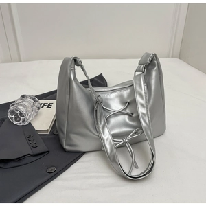 Silver metallic PU leather shoulder bag with decorative cross ribbons and bow on white background