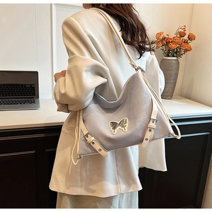 Detail of light blue faux leather crossbody bag with cream trim and butterfly metal logo
