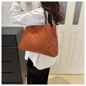 Gros plan d'un sac cabas en similicuir matelassé orange-brun avec coutures en losange