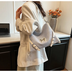 Detail of grey-blue tote bag with bow accent and adjustable white shoulder strap