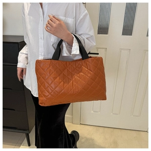 Détail d'un sac cabas matelassé en PU orange caramel avec une large bandoulière noire