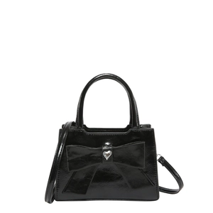 Glossy black patent leather handbag with large bow and heart rhinestone accent