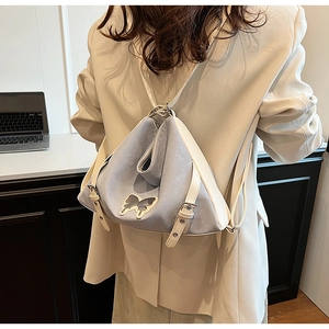 Blue and white bicolor convertible backpack on model in a minimalist home office setting