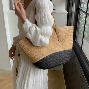Detail of a large woven tote bag featuring two-tone contrast and brown leather straps