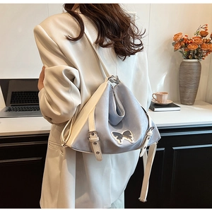 Detail of blue and beige triangle backpack featuring elegant butterfly embroidery
