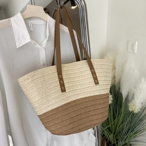 Close-up of woven straw tote bag with color-block design and premium leather handles