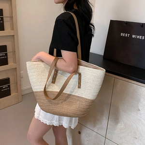 Detail of hand-woven straw tote with brown leather straps and contrast trim stitching
