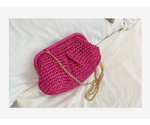 Detail view of fuchsia straw woven cloud bag with gold chain strap and metal clasp