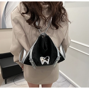 Detail of butterfly-shaped silver buckle on black velvet and silver leather backpack