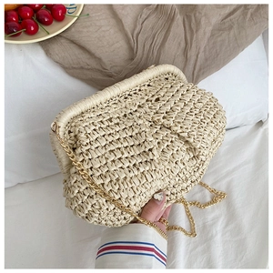 Detail of hand-woven straw bag with gold chain strap on a cozy lifestyle background