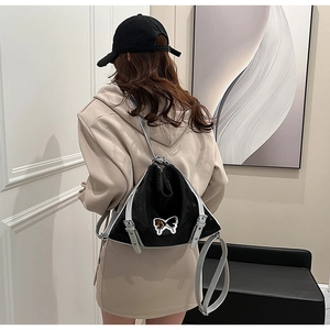 Detailed view of triangular black and silver backpack with butterfly metal ornament