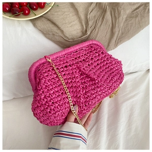 Close-up of bright pink straw woven crossbody bag with golden chain and clip closure