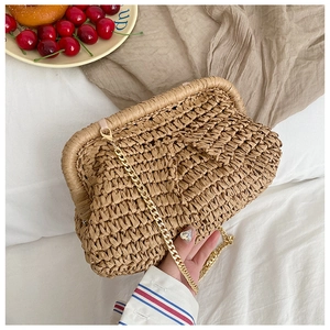 Detailed view of handmade straw woven clutch with gold metal clasp and chain strap