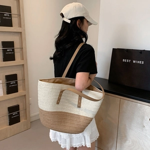 Women's two-tone woven straw tote bag with leather handles in a stylish summer aesthetic