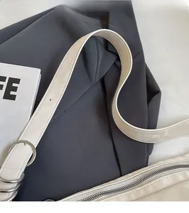 Detail of adjustable leather strap with silver metal rings on a cream shoulder bag