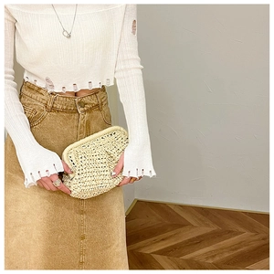 Detailed view of beige straw woven clutch bag with a puffy cloud-like design and texture