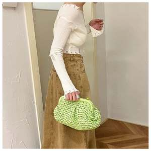 Close-up of vibrant green woven straw clutch with stylish spherical snap closure