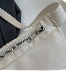 Close-up of a smooth silver zipper and leather texture on a white dumpling shoulder bag