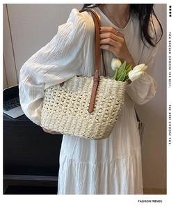 Detail of woven straw tote bag featuring hollow diamond patterns and brown leather straps