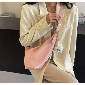 Detail of pink hobo bag with silver rings and a cute plush monster charm on the strap