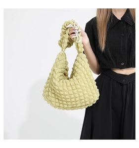 Close-up of pale yellow bubble textured hobo bag with white bow knot detail on strap