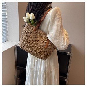 Close-up of a large capacity hand-woven straw bag with premium brown leather strap