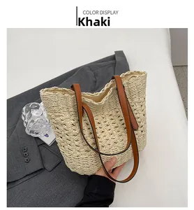 Detail of khaki straw woven tote bag with brown leather handles on neutral background