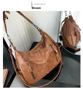 Detail view of a vintage brown leather bag with distressed texture and decorative zippers