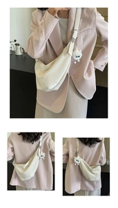 Detail of creamy white crescent shoulder bag with smooth satin texture and fun plush charm