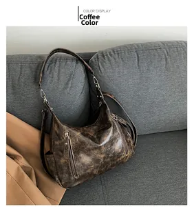 Detail view of coffee brown retro oil wax leather tote bag with functional zippers on sofa