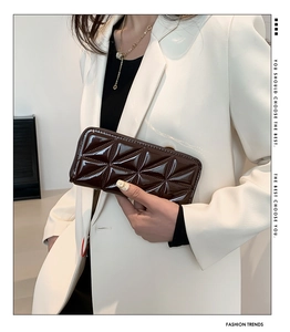 Detail of dark brown glossy patent leather wallet with geometric embossed pattern texture