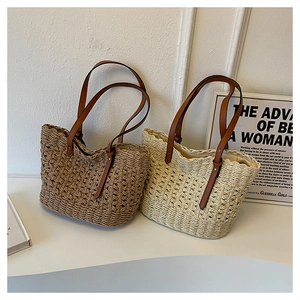 Detail of woven straw tote bags with leather handles in dark brown and beige tones