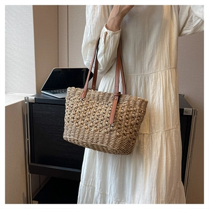 Detail of hand-woven straw tote bag with brown leather straps and texture closeup