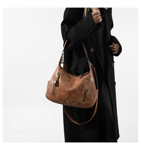 Brown vintage faux leather tote bag with dual straps worn over a black long winter coat