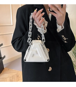 Detail view of white geometric PU handbag featuring embossed letters and silver chain handle