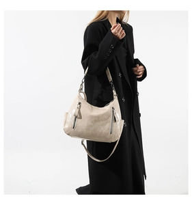 Beige high-capacity hobo bag shown in use with a chic black coat on white background
