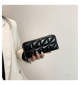 Close-up of a women's black quilted patent leather long wallet with gold zipper detail