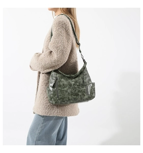 Detail view of large dark green retro shoulder bag with vertical metal zippers and leather texture